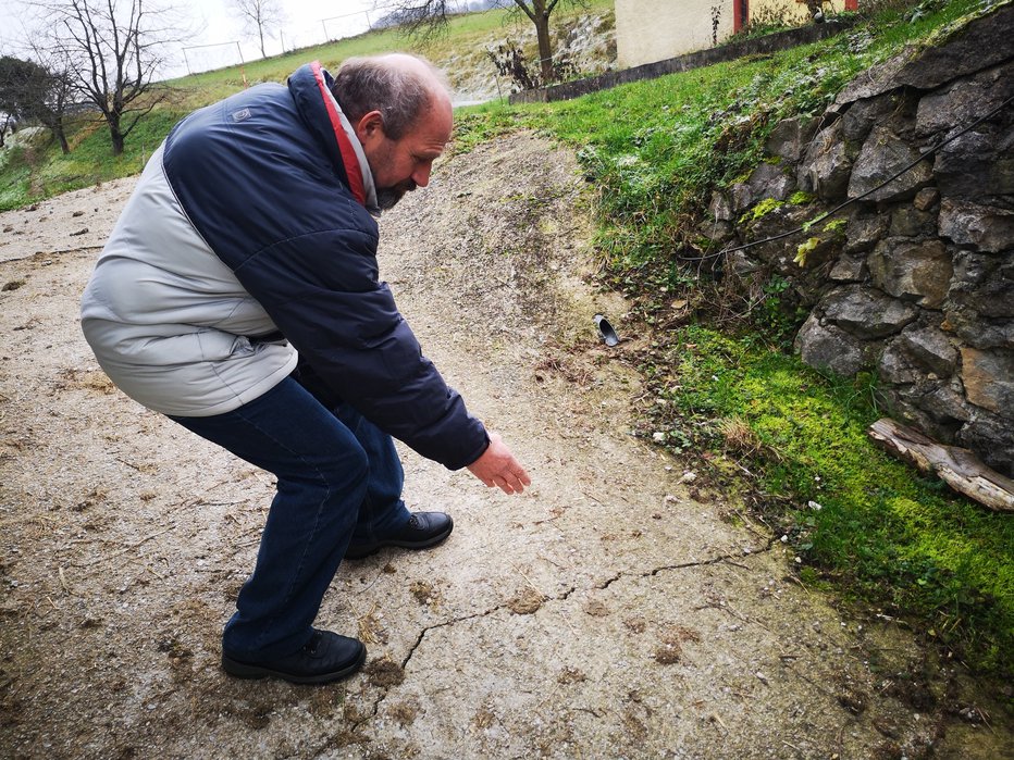 Fotografija: Martin Hrastnik kaže razpoke v tleh, ki se vsak dan večajo. FOTO: Mojca Marot