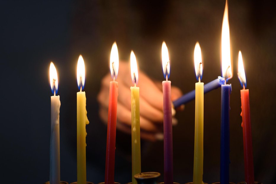 Fotografija: A person lighting Hanukkah Candles in a menorah. People celebrate Chanukah by lighting candles on a menorah, also called a Hanukiyah. Each night, one more candle is lit.