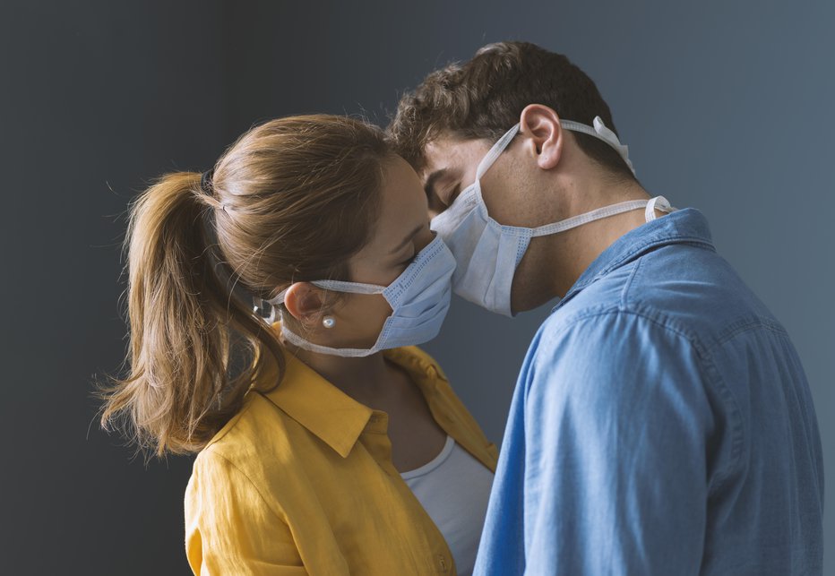 Fotografija: Young millennials couple wearing protective face masks and kissing each other, virus spread prevention and people concept