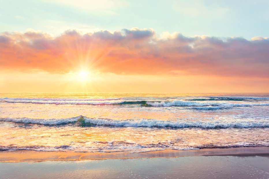 Fotografija: Ocean wave on the beach at sunset time, sun rays