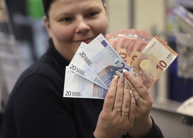 A cashier displays euro banknotes before a shop opens in Vilnius January 1, 2015. Lithuania joined the euro zone at the stroke of midnight on Thursday, hoping to anchor itself in Europe as its former master Russia flexes its military muscle in the region. REUTERS/Ints Kalnins (LITHUANIA - Tags: BUSINESS POLITICS) - RTR4JSQB/ izvorno ime datoteke: RTR4JSQB.jpg FOTO: Reuters