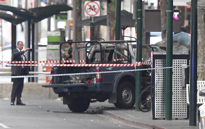 Lokalni mediji so objavili fotografije visokega moškega, oblečenega v črno tuniko, ki ob gorečem avtomobilu maha z rokami in poskuša z nožem zabosti policiste. FOTO: James Ross, AP