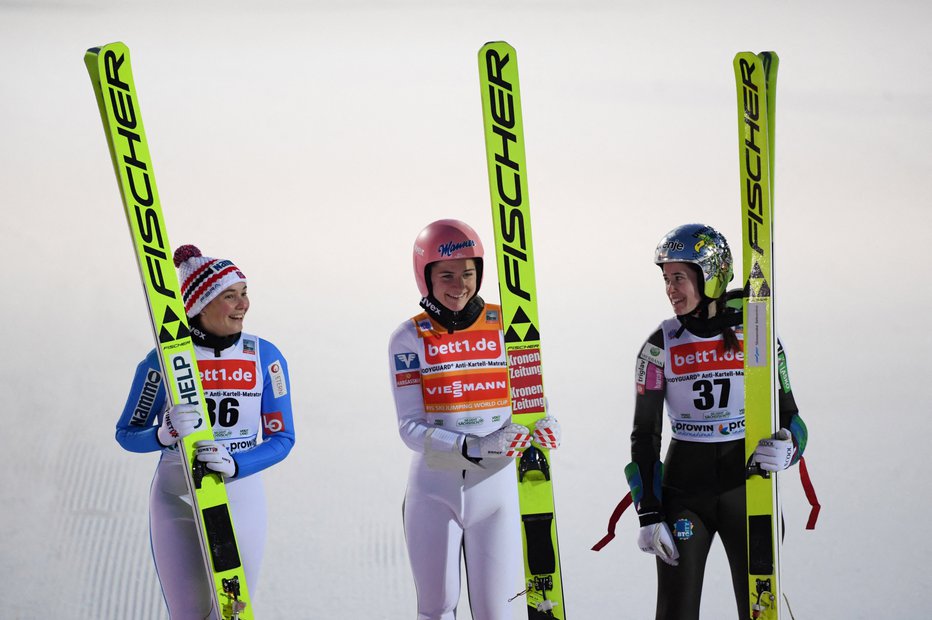 Fotografija: Urša Bogataj (desno) se je včeraj v Klingenthalu veselila tretjega mesta. Nasmejani sta bila tudi avstrijska zmagovalka Marita Kramer (na sredini) in drugouvrščena Norvežanka Silje Opseth (levo). FOTO: Annegret Hilse/Reuters
