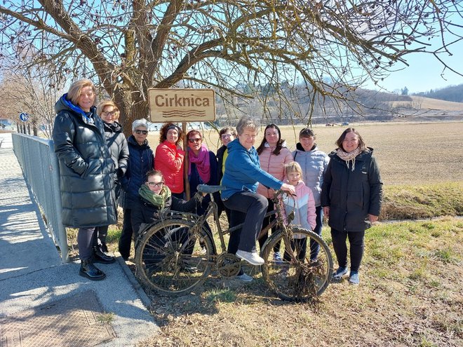 Člani KUD Marice Kerenčič ob tabli potoka Cirknica, iz katerega so potegnili tudi kolo. FOTO: Osebni Arhiv
