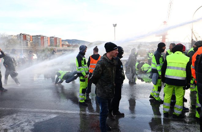 Čeprav so pred dnevi v Trstu uporabili vodni top in solzivec, protestniki še naprej vztrajajo. FOTO: Stringer/AFP
