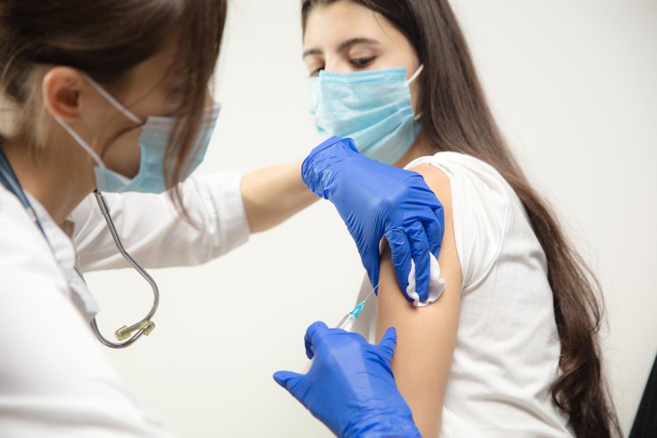 Fotografija: Protect. Close up doctor or nurse giving vaccine to patient using the syringe injected. Works in face mask. Protection against coronavirus, COVID-19 pandemic and pneumonia. Healthcare, medicine.
