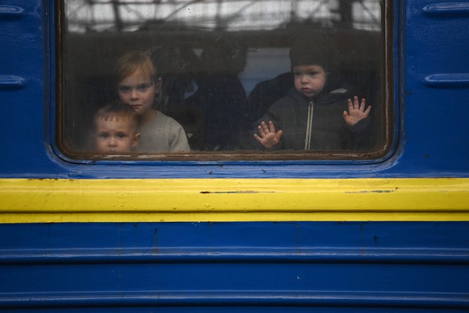 Otroci gledajo skozi okno vagona, ko se vlak pripravlja na odhod s postaje v Lvovu na zahodu Ukrajine, na poti proti mestu Užgorod blizu meje s Slovaško. FOTO: Daniel Leal/AFP
