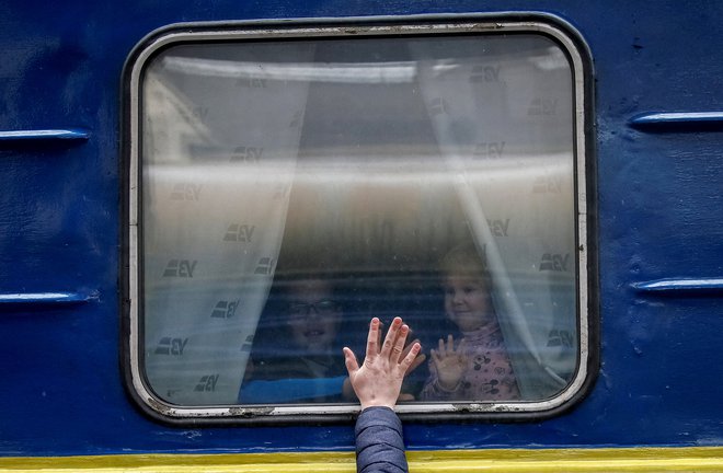 Otroci gledajo iz evakuacijskega vlaka iz Kijeva v Lvov, ko se poslavljajo od očeta na osrednji železniški postaji v Kijevu. FOTO: Gleb Garanich/Reuters
