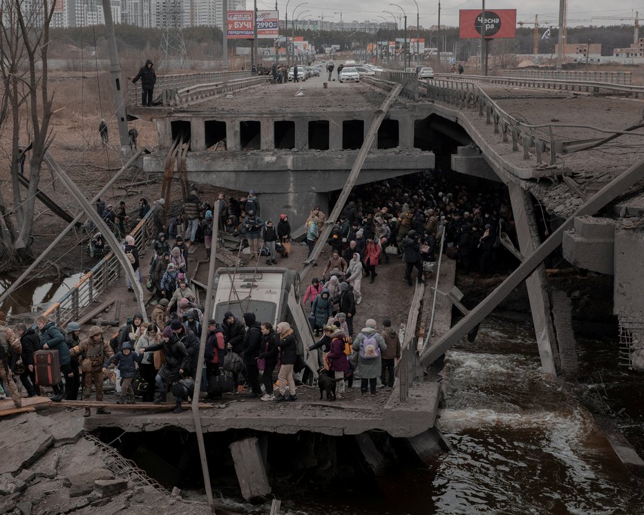 Fotografija: Ljudje, ki skušajo zapustiti mesto Irpin v bližini Kijeva, ob prečkanju ruševin mostu. FOTO: Agencja Wyborcza.pl via Reuters
