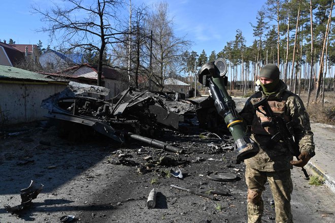 Ukrajinski vojak drži lahko protitankovsko orožje, ki je bilo uporabljeno za uničenje ruskega oklepnega osebnega transporterja v Irpinu severno od Kijeva. FOTO: Sergei Supinsky/AFP
