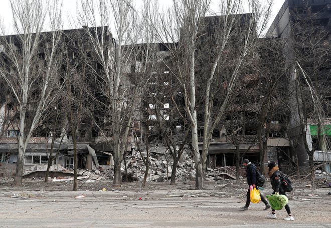 Lokalni prebivalec hodi mimo uničene zgradbe v Mariupolju. FOTO: Alexander Ermochenko/Reuters

