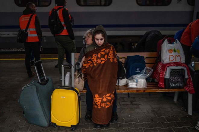 Ukrajinski begunci čakajo, da se vkrcajo na vlak na poti v Varšavo na železniški postaji v Przemyslu, blizu poljsko-ukrajinske meje. FOTO: Angelos Tzortzinis/AFP
