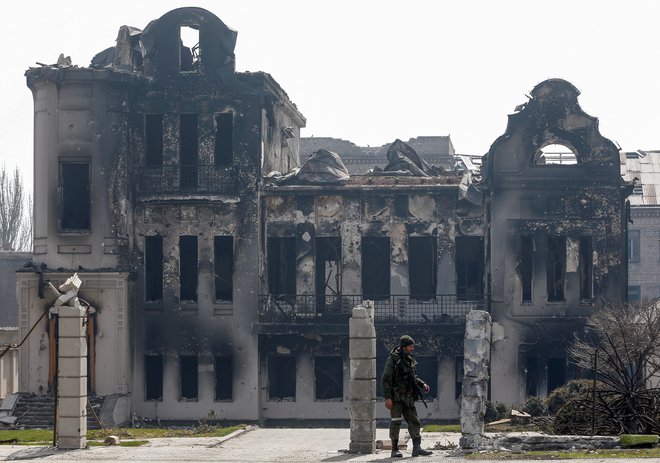 Proruski vojak pred uničenim objektom v Mariupolju. FOTO: Alexander Ermochenko/Reuters
