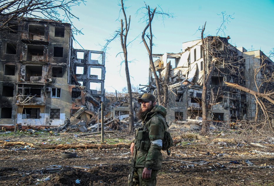 Fotografija: Čečenski vojak pozira fotografu pred uničenimi stanovanjskimi stavbami v Mariupolju. FOTO: Reuters
