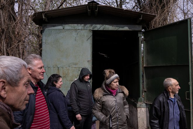 Ljudje stojijo pred vhodom v bombno zaklonišče kemične tovarne Azot v Luganski regiji. FOTO: Marko Djurica/Reuters
