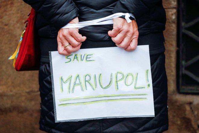 Ženska z znakom 'rešite Mariupolj' z zvezanimi rokami na hrbtu na protestu v Pragi na Češkem. FOTO: David W Cerny/Reuters
