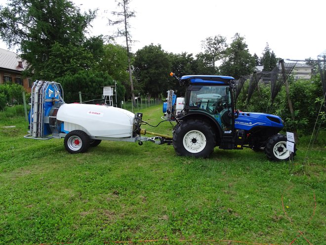 Ozkokolotečni traktor new holland T4 100 F in Zupanov elektrostatični pršilnik ZM 1500 DT maxi-O. Traktor ima 73 kW nazivne moči.