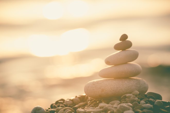 folded pyramid Zen pebble stones on the sea beach at sunset