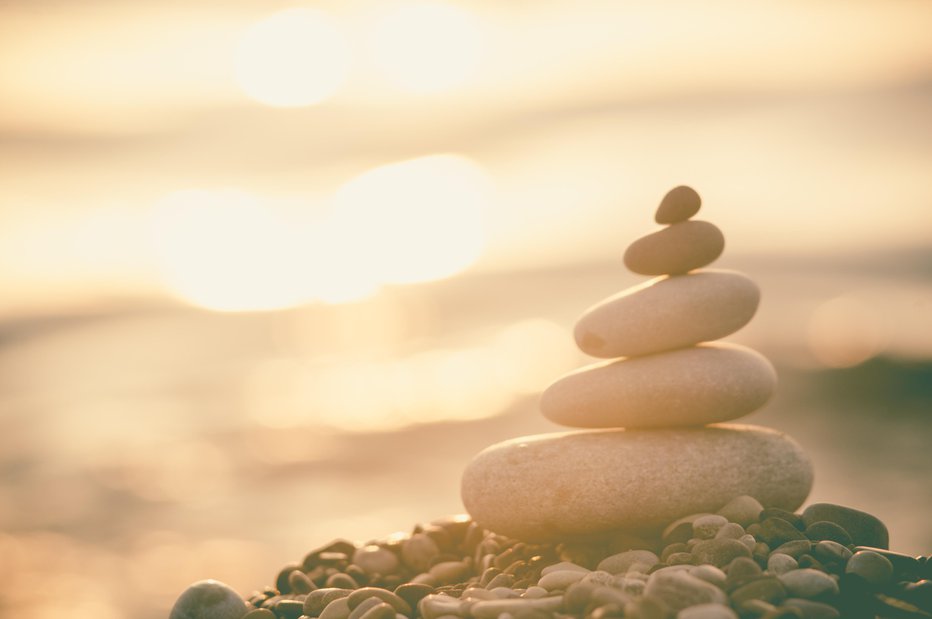 Fotografija: folded pyramid Zen pebble stones on the sea beach at sunset