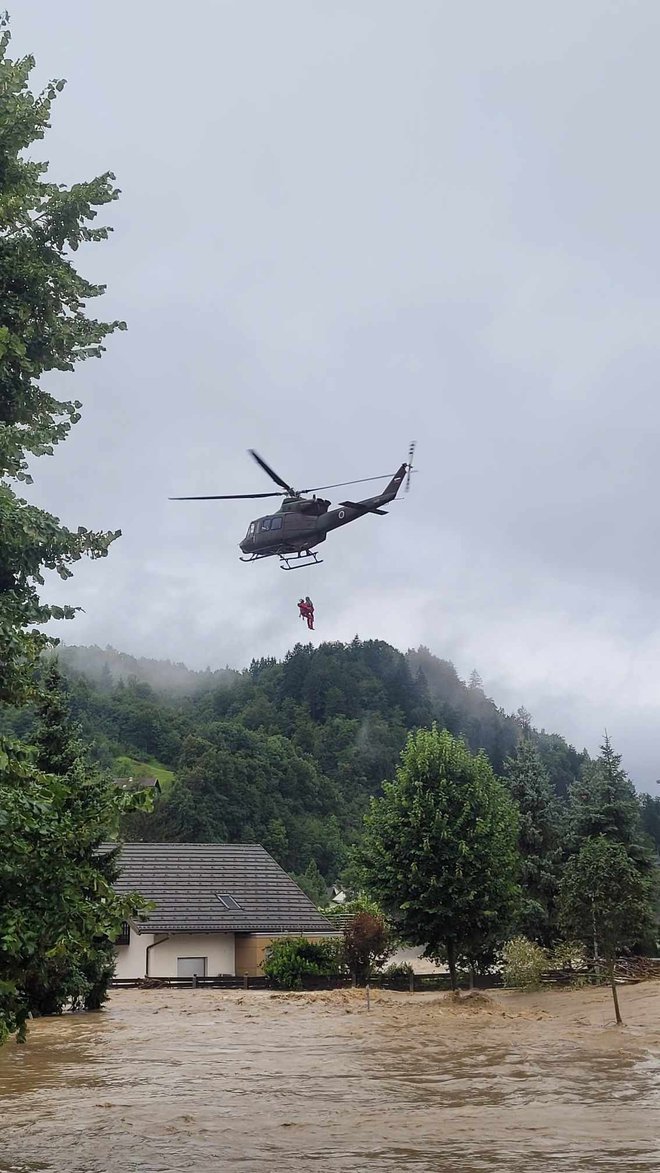 V Škofji Loki so iz ogrožene hiše s helikopterjem rešili štiri stanovalce, med njimi invalida. FOTO: GRZS