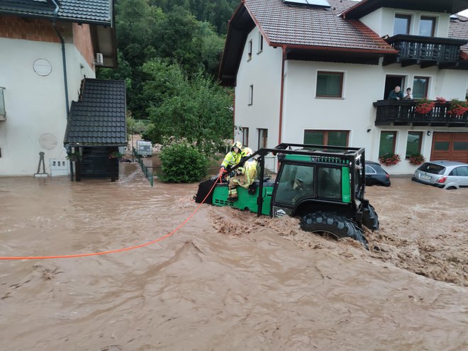 Pri reševanju nepokretne osebe so si gasilci v Gorenji vasi pomagali s traktorjem, saj se drugače niso mogli prebiti do poplavljene hiše. FOTO: PGD Gorenja vas