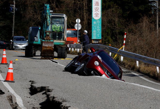 Avto je obtičal v razpoki na cesti, ki je nastala ob potresu. FOTO: Kim Kyung-hoon, Reuters