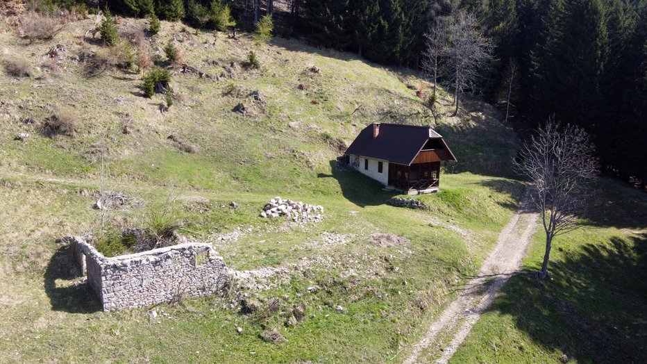 Fotografija: Na edini uravnavi nas pričakajo ruševine nekdanje planšarije in poleg nje lovski dom. FOTO: Janez Mihovec