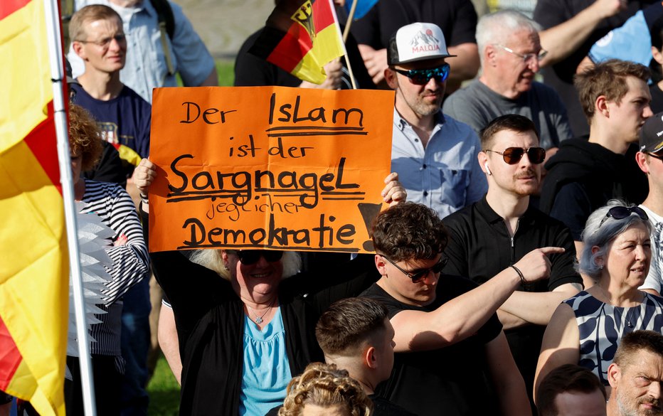 Fotografija: Volivec stranke AfD drži plakat z napisom »Islam je zadnji žebelj v krsto vsake demokracije«. FOTO: Heiko Becker Reuters