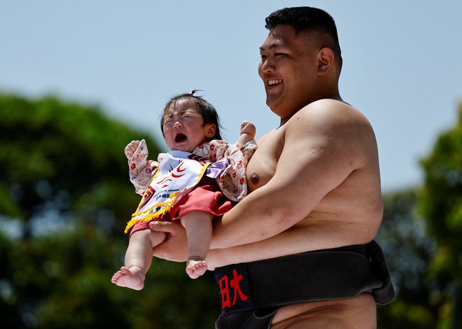 NIč kaj zadovoljen otrok v rokah sumo borca, kar naj bi prispevalo k zdravju otroka in odganjanju zlih duhov. FOTO: Issei Kato/Reuters