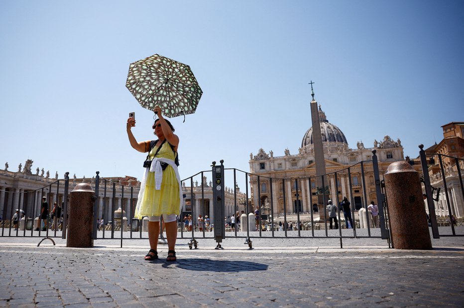 Fotografija: V Rimu se je ženska zaščitila z dežnikom. FOTO: Guglielmo Mangiapane Reuters