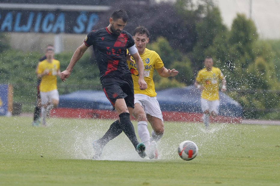 Fotografija: Gostujoči kapetan Slobodan Jakovljević je na namočenem igrišču dosegel pomemben gol in v obrambi onemogočil domačega aduta Martina Pečarja. FOTO: Leon Vidic