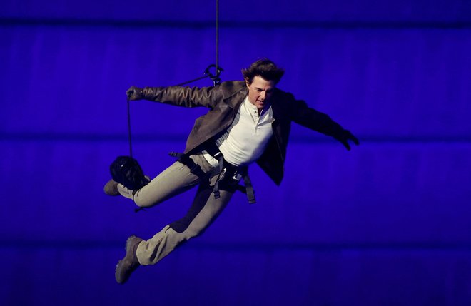 Filmski zvezdnik Tom Cruise se je med zaključno slovesnostjo v Parizu spustil s strehe stadiona Stade de France. FOTO: Phil Noble/Reuters