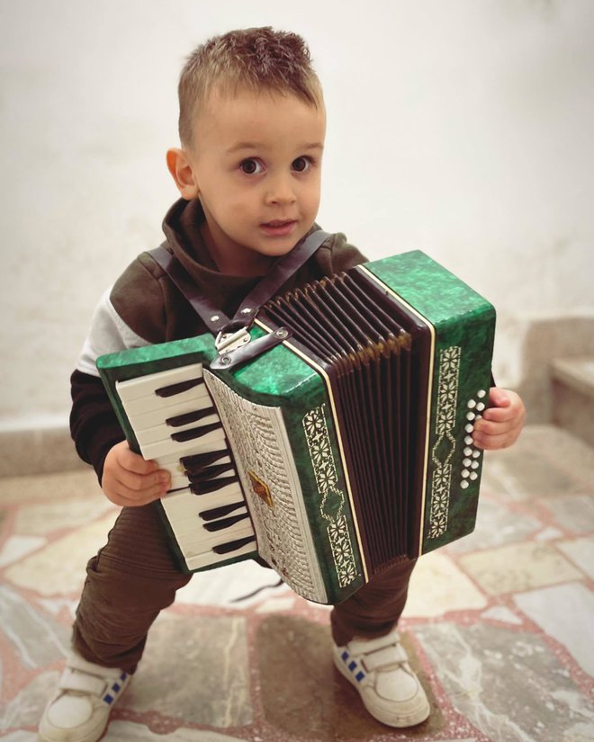 Štiriletni Nai Kukar, po vzoru staršev, že zdaj rad raztegne meh harmonike.