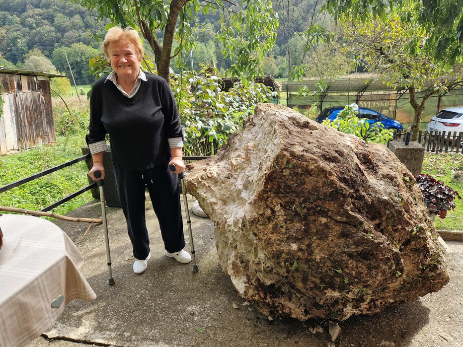 Fotografija: 83-letna Zinka ob skalni gmoti, ki je priletela po strmem bregu do hiše. FOTO: Tanja Jakše Gazvoda