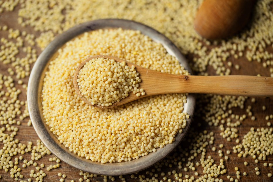 Fotografija: Millet groats in spoon above bowl, top view