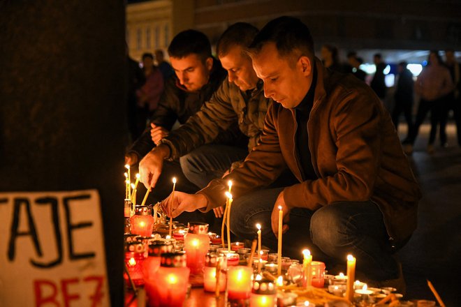 Žalujoči pred želežniško postajo v Novem sadu prižigajo sveče in nosijo cvetje v spomin na žrtve. FOTO: Nenad Mihajlovic Afp