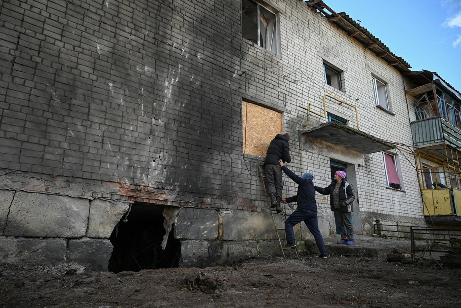 Fotografija: Prebivalci nameščajo OSB ploščo namesto razbitega okna v stanovanjski hiši, ki jo je med ruskim napadom na Ukrajino zadel dron, v vasi Krasylivka. 3. november 2024. FOTO: Maksym Kishka Reuters