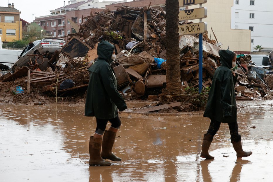 Fotografija: Ljudje po močnem deževju, ki je povzročilo hude poplave, hodijo po ulici ob blatu v kraju Paiporta v bližini Valencie v Španiji, 3. novembra 2024. FOTO: Eva Manez Reuters