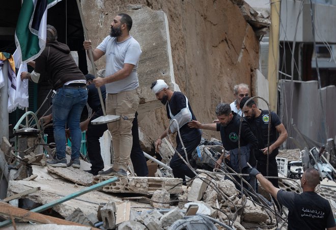 Moški se sprehaja med ruševinami po napadu. FOTO: Adnan Abidi Reuters