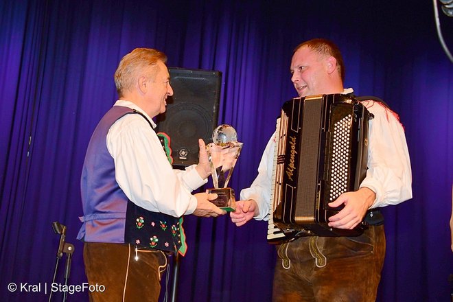 Tomaž Hribar, harmonikar in vodja, prejema nagrado iz rok organizatorja Rudija Mallyja. FOTO: Stage Foto