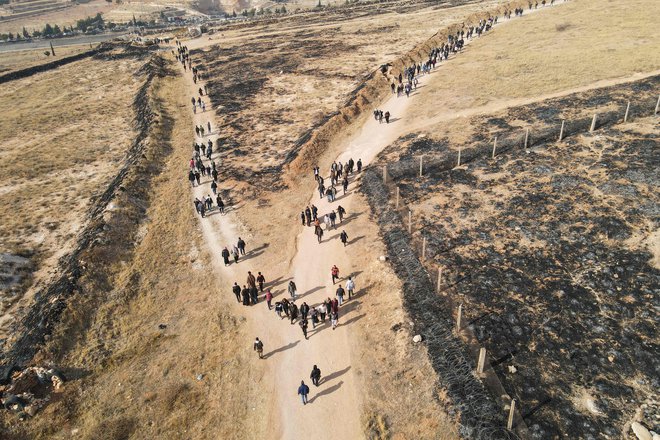 An aerial photo shows people walking on a dirt road leading to the Saydnaya prison as Syrian rescuers and experts search for potential hidden basements at the facility in Damascus on December 9, 2024. Syrian rescuers searched the Saydnaya jail, synonymous with the worst atrocities of ousted president Bashar al-Assad's rule, as people in the capital on December 9 gathered to celebrate a day after Assad fled while Islamist-led rebels swept into the capital, ending five decades of brutal rule over a country ravaged by one of the deadliest wars of the century. (Photo by Mohammed AL-RIFAI/AFP) FOTO: Mohammed Al-rifai Afp