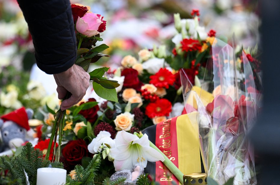 Fotografija: Sveče, igrače in cvetlični pokloni v bližini božičnega sejma Alter Markt, kjer je v petek zvečer skozi zasilni izhod v množico ljudi zapeljal avtomobil. FOTO: Annegret Hilse Reuters