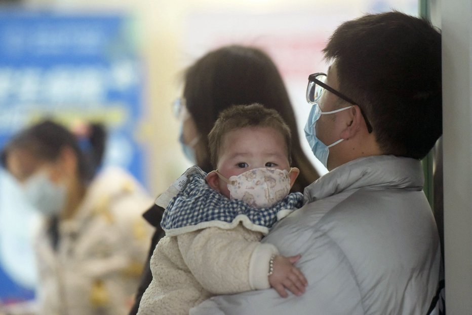 Fotografija: Dojenček z obrazno masko z družinskimi člani v čakalnici na pediatričnem oddelku bolnišnice v mestu Hangzhou 6. januarja 2025. Peking je priznal porast primerov gripi podobnega HMPV, zlasti med otroki. FOTO: Str Afp