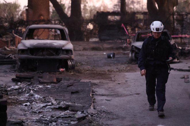 Uslužbenka iz službe za iskanje in reševanje okrožja Marin pregleduje požgano posestvo. FOTO: Mario Anzuoni Reuters